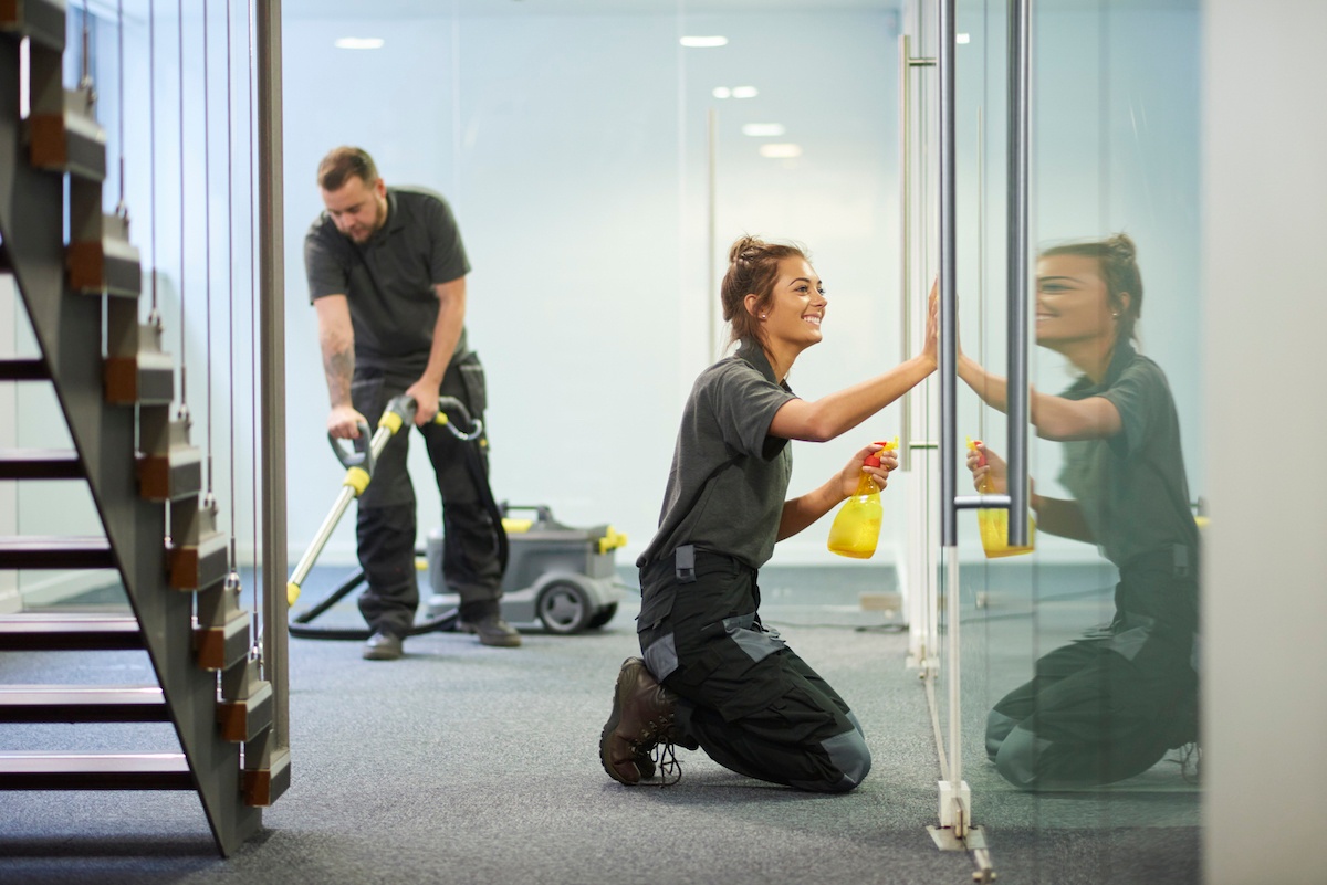 Day porter crew cleaning an office glass partition and carpet